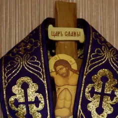 Drewniany krzyż z ikoną Jezusa i napisem "ЦАРЬ СЛАВЫ" (INRI), ozdobiony fioletową tkaniną ze złotymi zdobieniami.