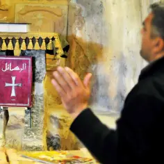 Mężczyzna modli się przed czerwoną księgą z krzyżem. Różnorodność religii w Kazachstanie jest fascynująca.