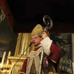 Arcybiskup Grzegorz Ryś w szatach liturgicznych z pastorałem, przemawia przy mikrofonie.
