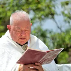 Duchowny w białej szacie czyta księgę, zastanawiając się, czy antykoncepcja to grzech.