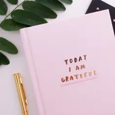 Różowy notes z napisem "TODAY I AM GRATEFUL" i złotym długopisem. Idealny do codziennej modlitwy dziękczynnej.
