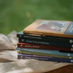 Stos książek o tematyce religijnej, w tym "Serce Eucharystii", na tle zieleni.