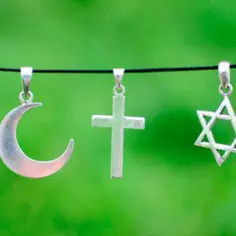 Srebrny półksiężyc, krzyż i gwiazda Dawida wiszą obok siebie, symbolizując pokój między islamem a chrześcijaństwem.