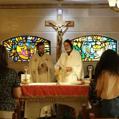 Nabożeństwo grekokatolickie. Dwóch księży w szatach liturgicznych przy ołtarzu, w tle witraże i krzyż.