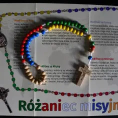 Kolorowy różaniec misyjny z drewnianym krzyżykiem i medalikiem, ułożony na kartce z modlitwami za różne kontynenty.