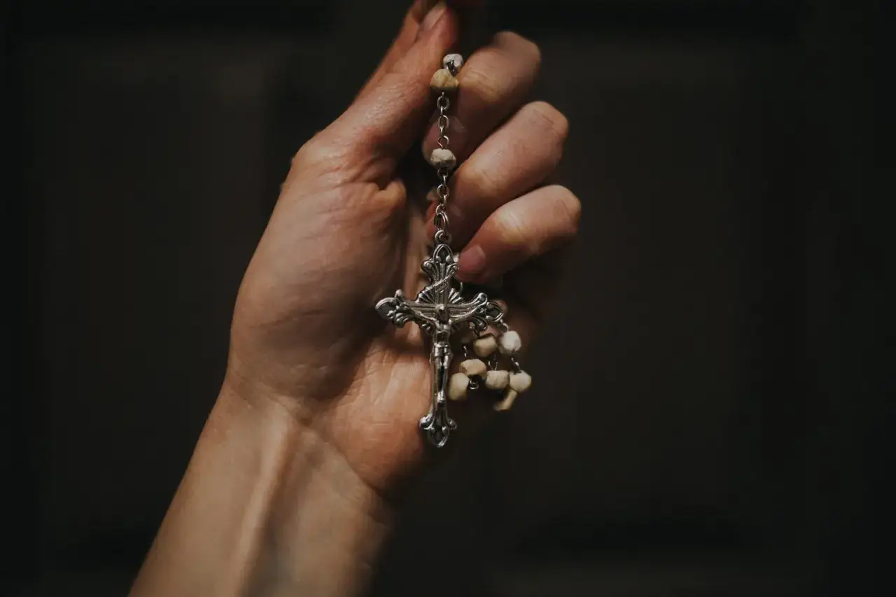 Dłoń trzyma różaniec z krzyżem. Czuć w tym obrazie modlitwę za brata.