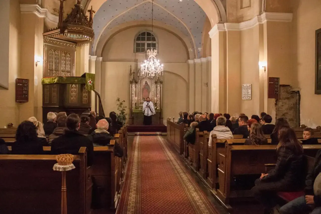 Nabożeństwo w kościele luteran. Ludzie siedzą w ławkach, a pastor stoi przy ołtarzu.